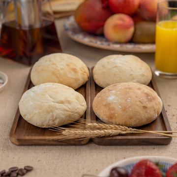 Wooden tray with bagnat bread on a table with fruits and drinks