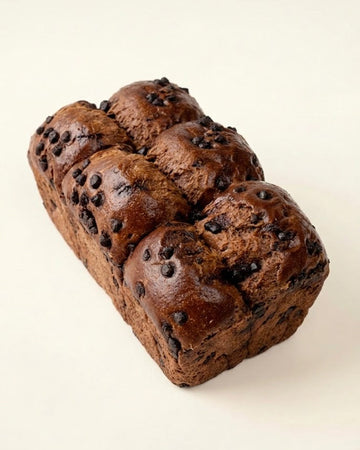 Chocolate Brioche loaf cake with visible chocolate chips on a beige background