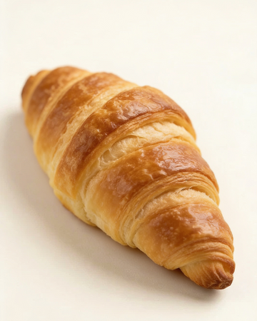 A single golden-brown flaky croissant photographed on a clean white background.
