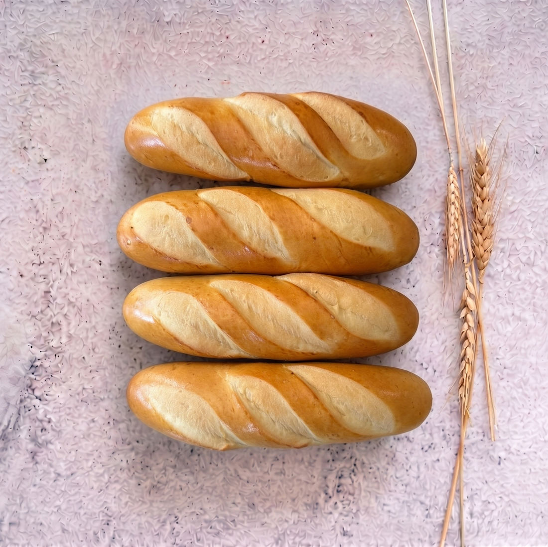 Loaves of milk bread on wooden trays with a breakfast setting including coffee, orange juice, and fruit.